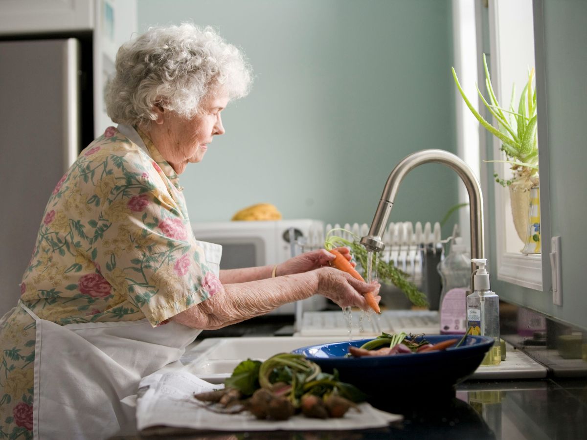 elderly woman washing carrots